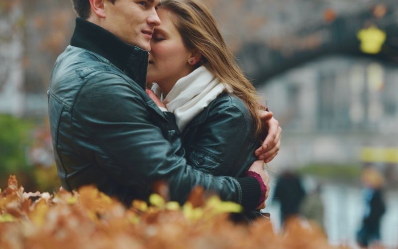 couple hugging in the fall surrounded by leaves