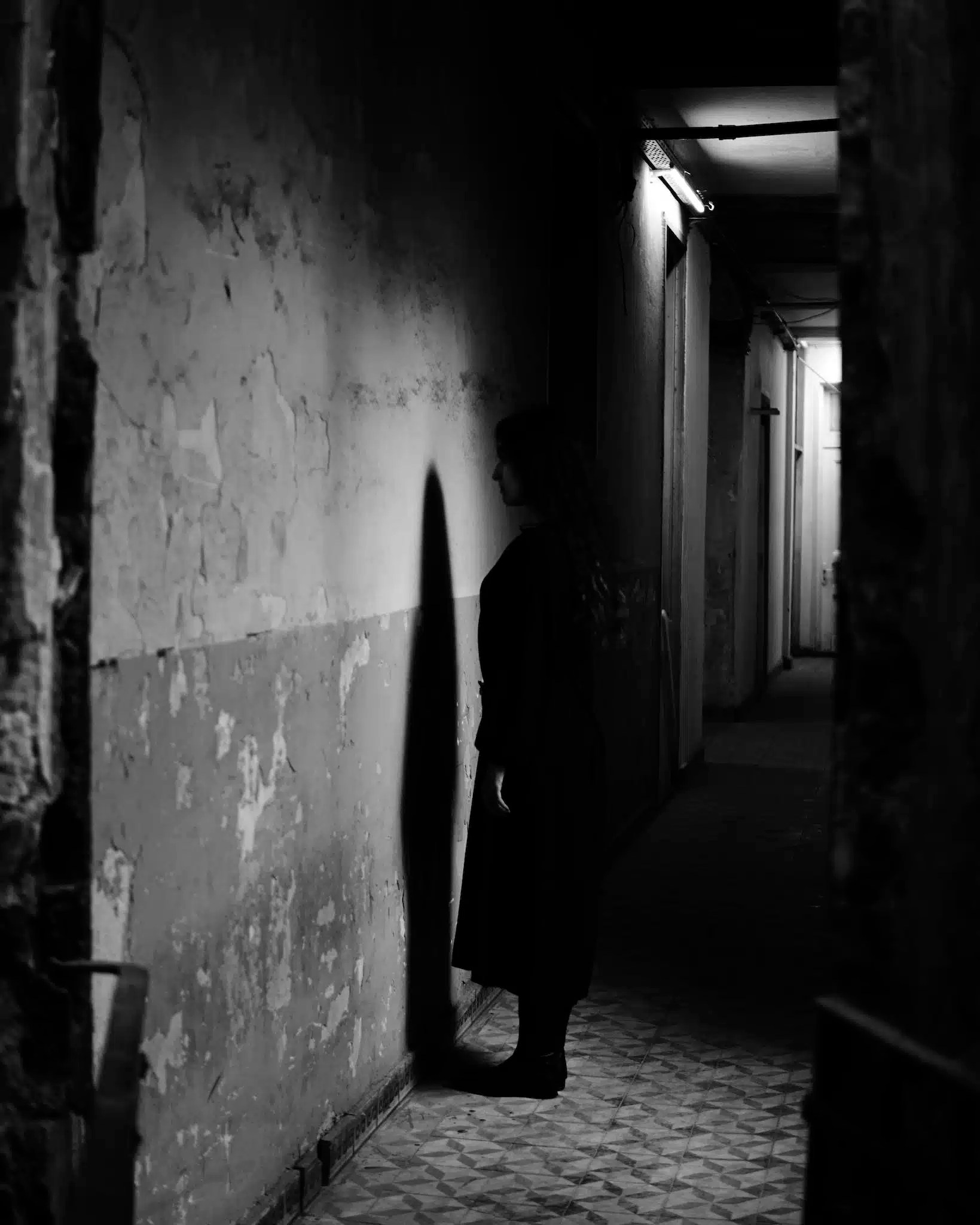 Grayscale Photo of a Woman Facing the Wall