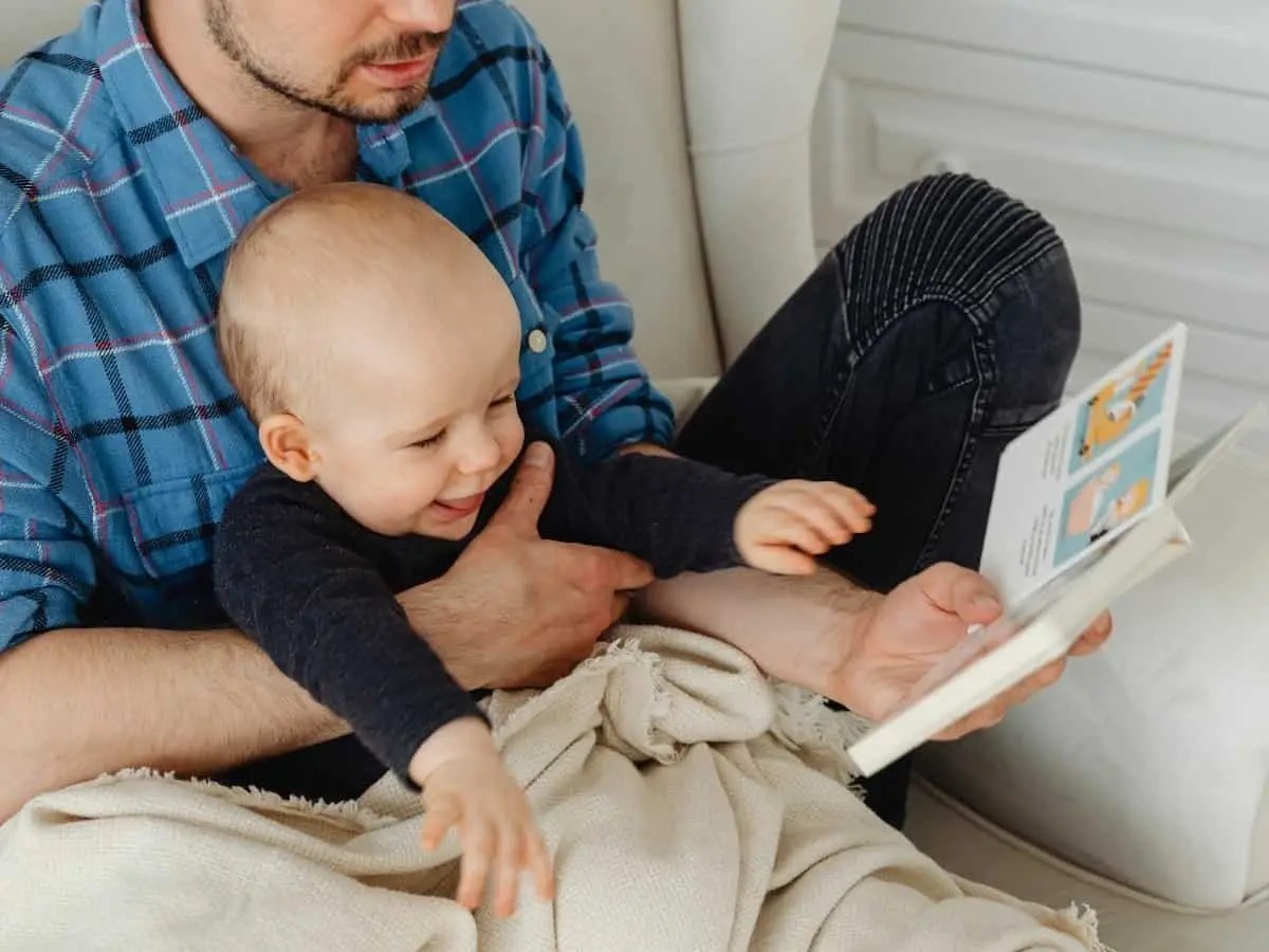 A baby being held and red to my a adult man