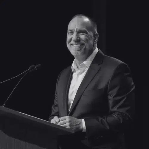 Smiling man in suit speaking at podium.
