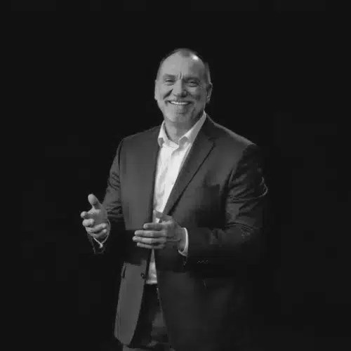 Smiling man in a suit, clapping hands.