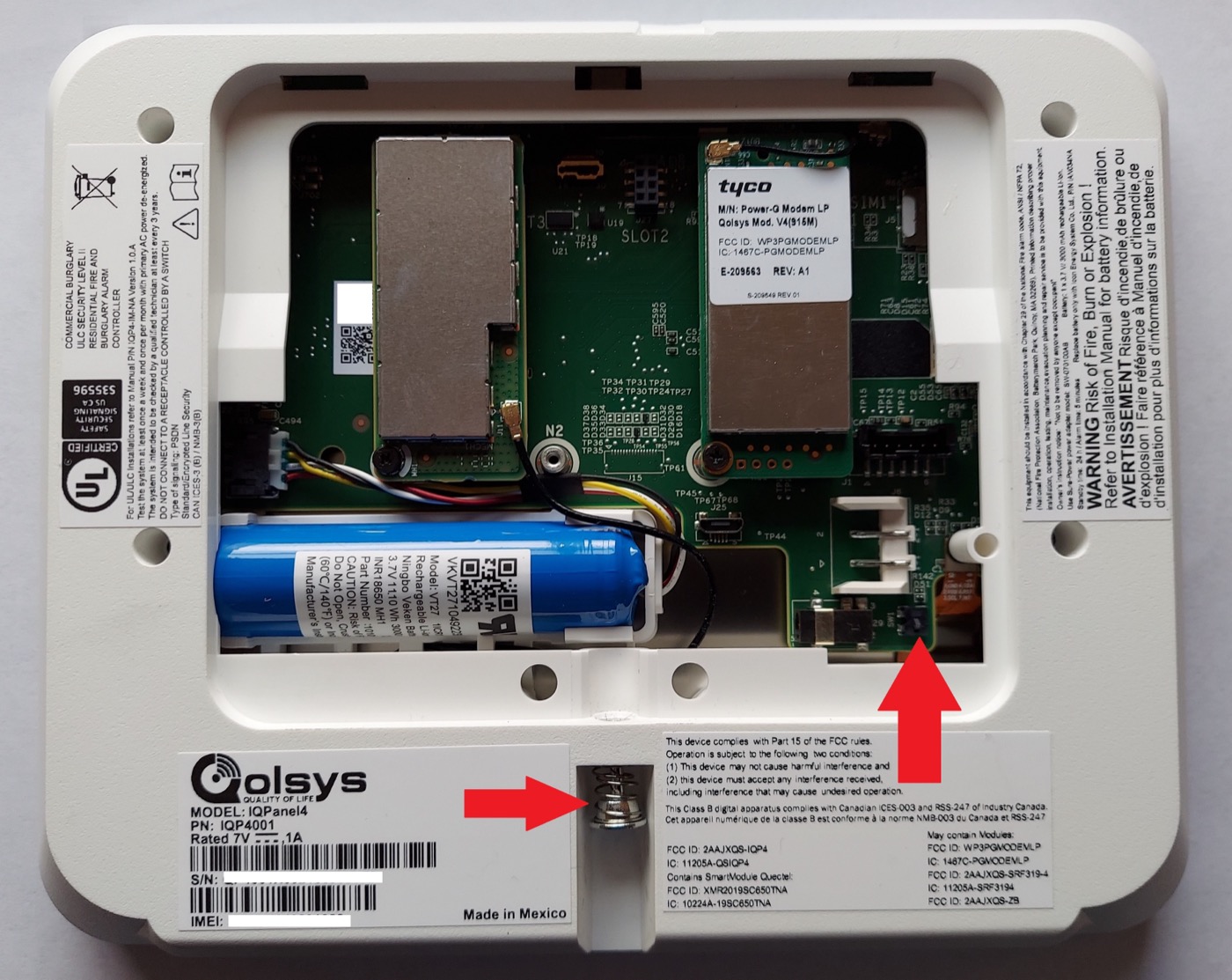 Inside the IQ Panel 4: the arrows mark the tamper switch (bottom right) and the locking-screw post (bottom center) — the two things to check when a tamper alert appears.