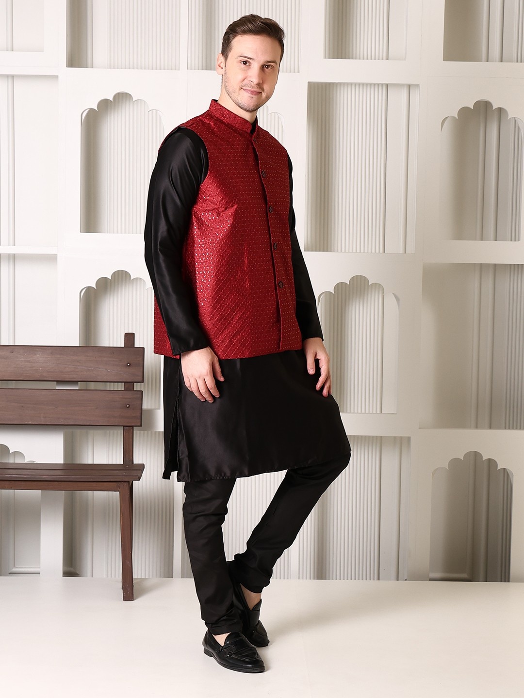 "Man wearing black satin kurta pajama set with maroon brocade Nehru jacket, mandarin collar, paired with black loafers, Shrobh Ethnic wedding wear"