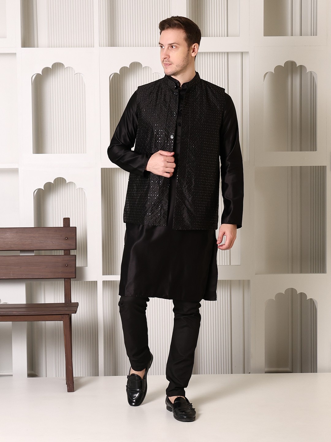 "Man wearing black satin kurta pajama set with maroon brocade Nehru jacket, mandarin collar, paired with black loafers, Shrobh Ethnic wedding wear"
