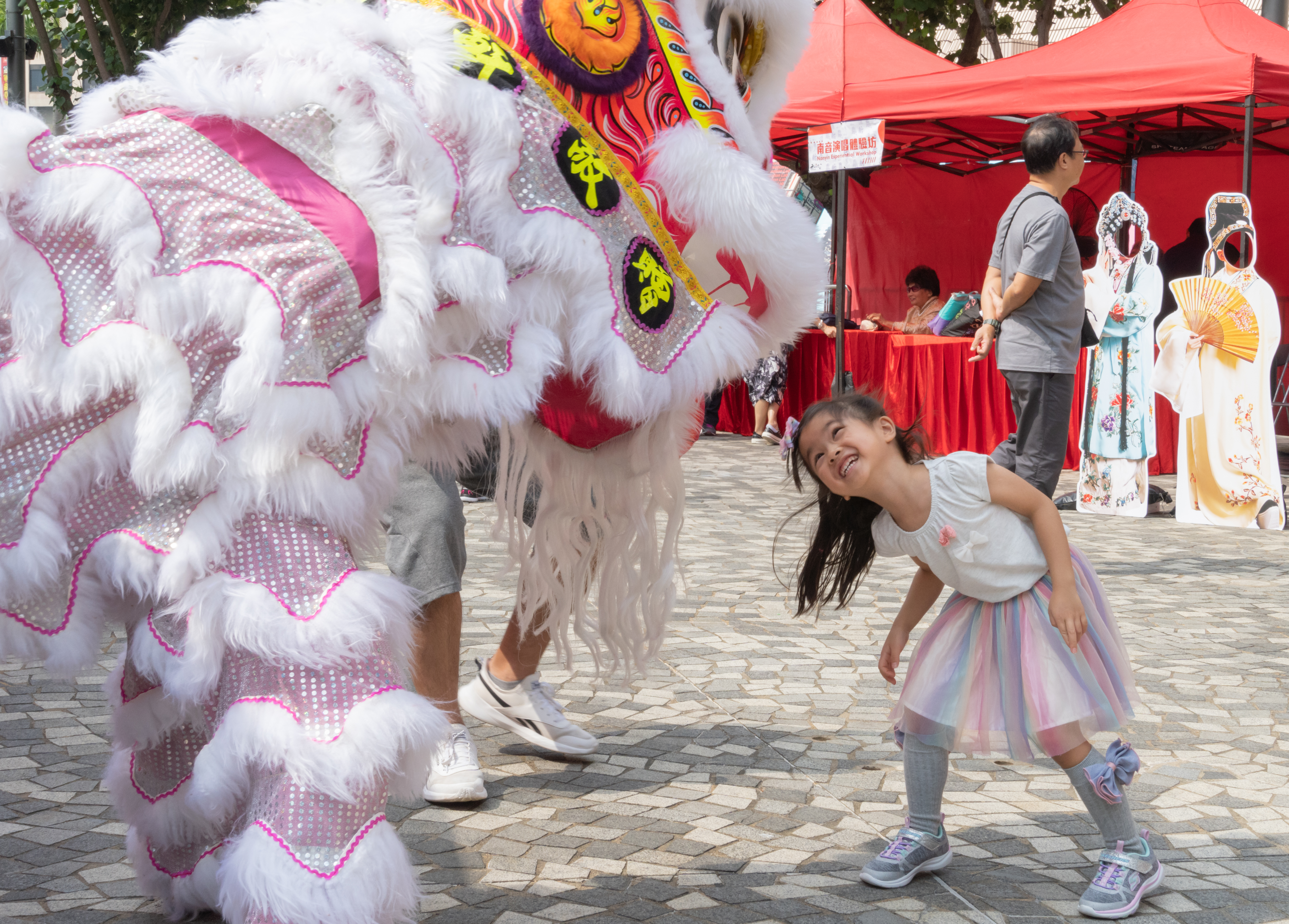 A little girl happily interacting with the lion-dance performers in a workshop