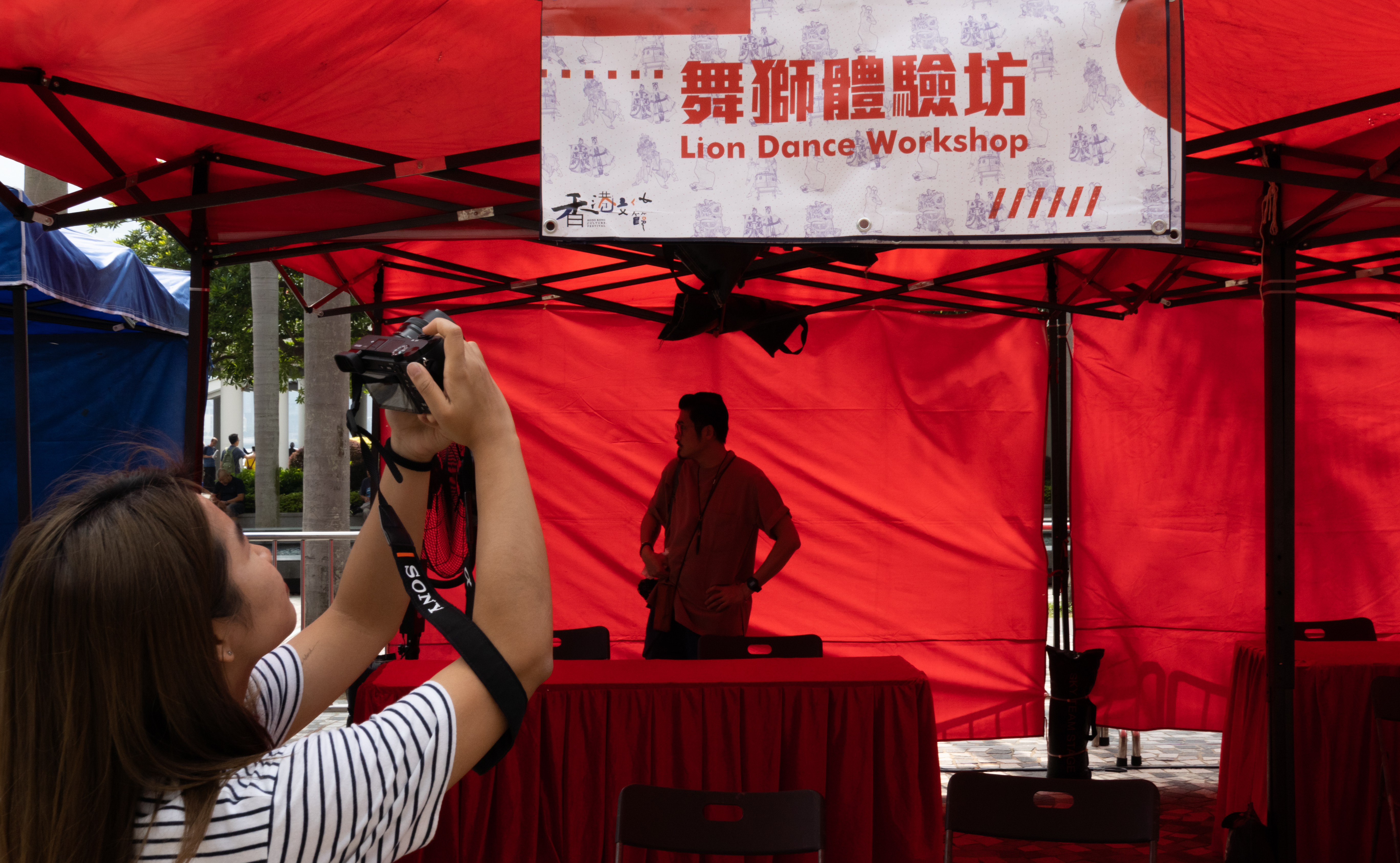 A woman taking pictures of the board of lion dance workshop poded by HK ICM