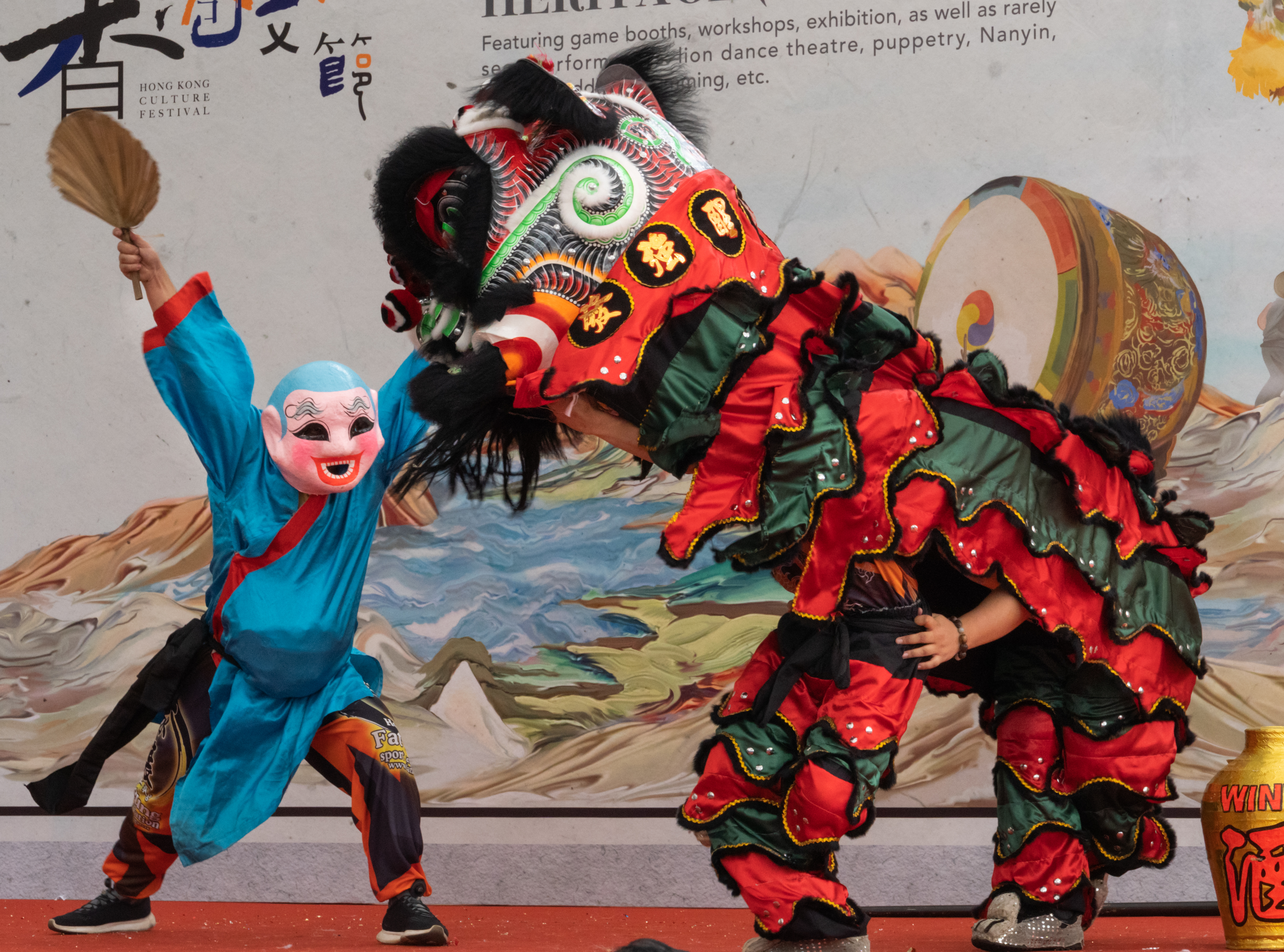 Man interacting with the lion as a clown with a funny mask in order to make the lion dance