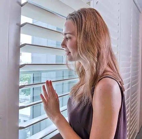 Client looking through her new bedroom window shutters