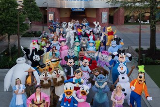 Large group of Disney character mascots posing for a group photo outside an Animation building.