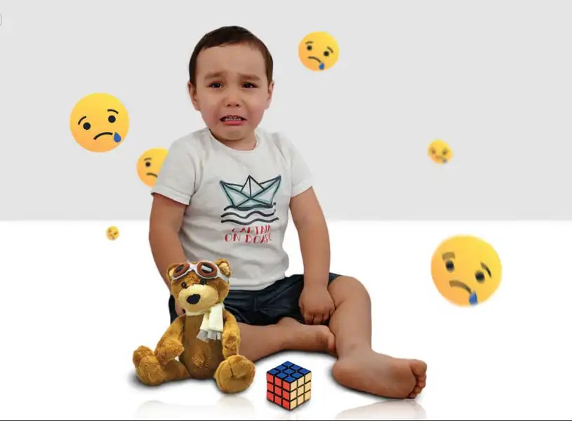 anak kecil menangis duduk di lantai dengan boneka dan rubik ekspresi sedih