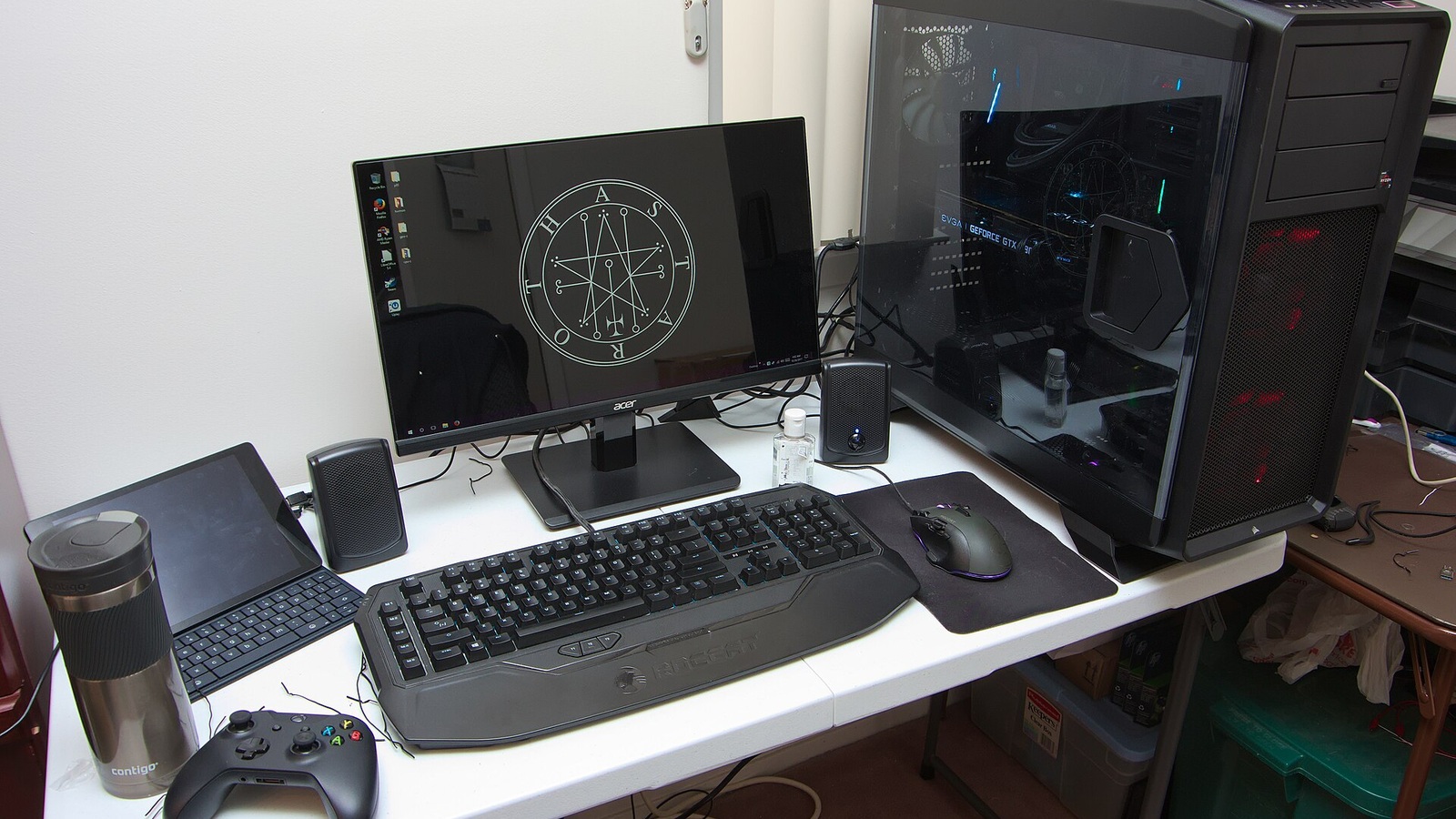 Mesa com computador gamer, monitor, teclado, mouse e controle de videogame.