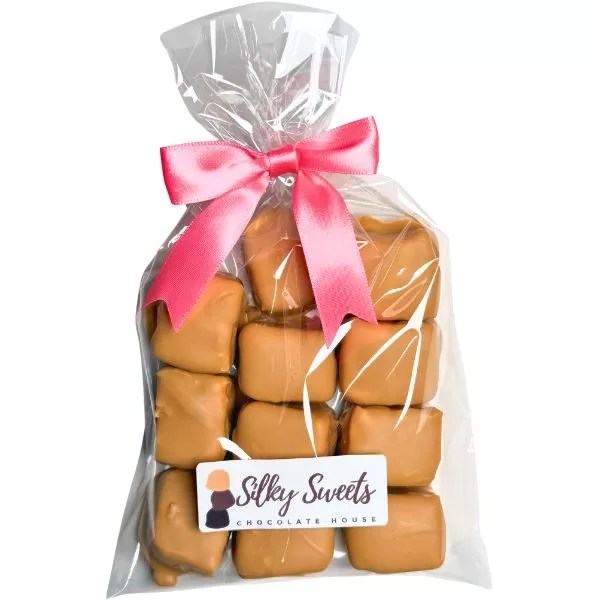 clear cellophane bag measuring 6x10in with 11 blonde chocolate -covered marshmallows with a store label on the front that says silky sweets chocolate house and a pink bow to tie the bag