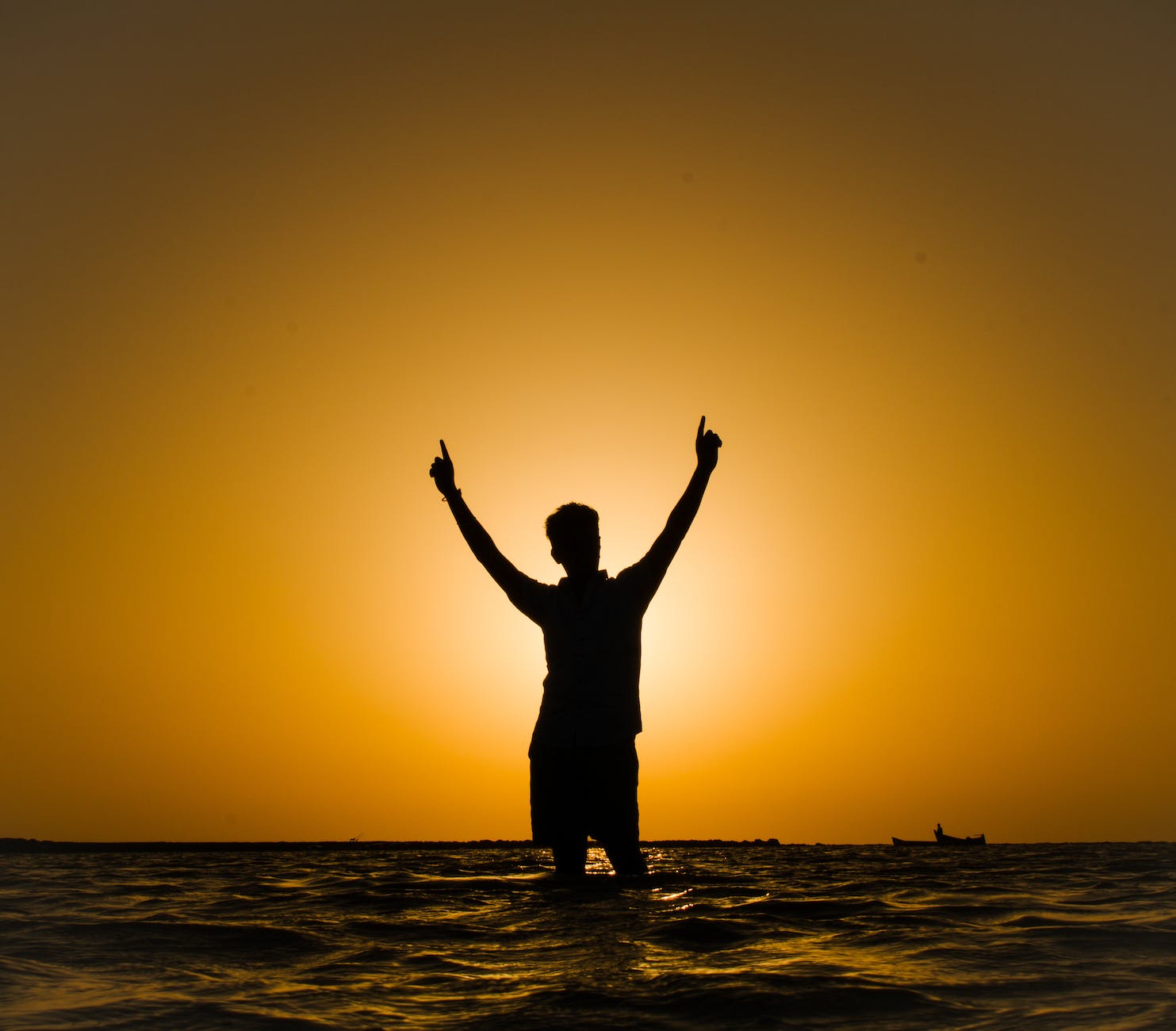 a person standing in water at sunset