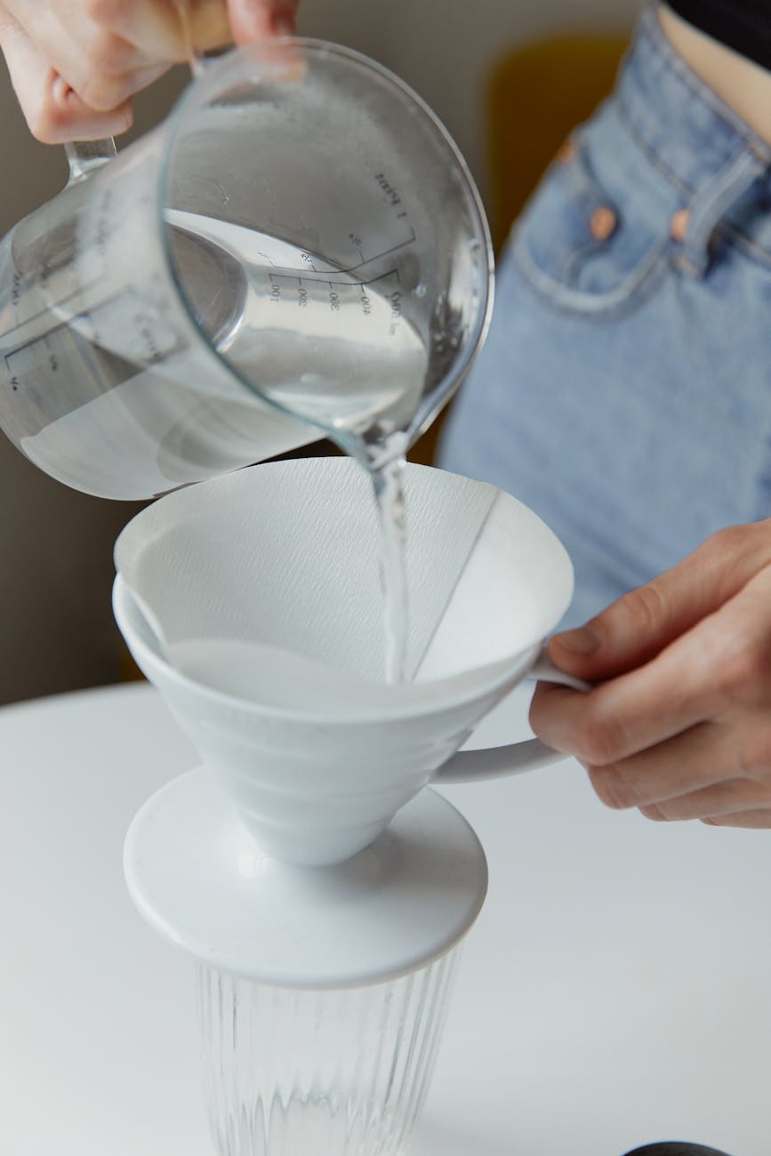 a hand pouring hot water on a cup