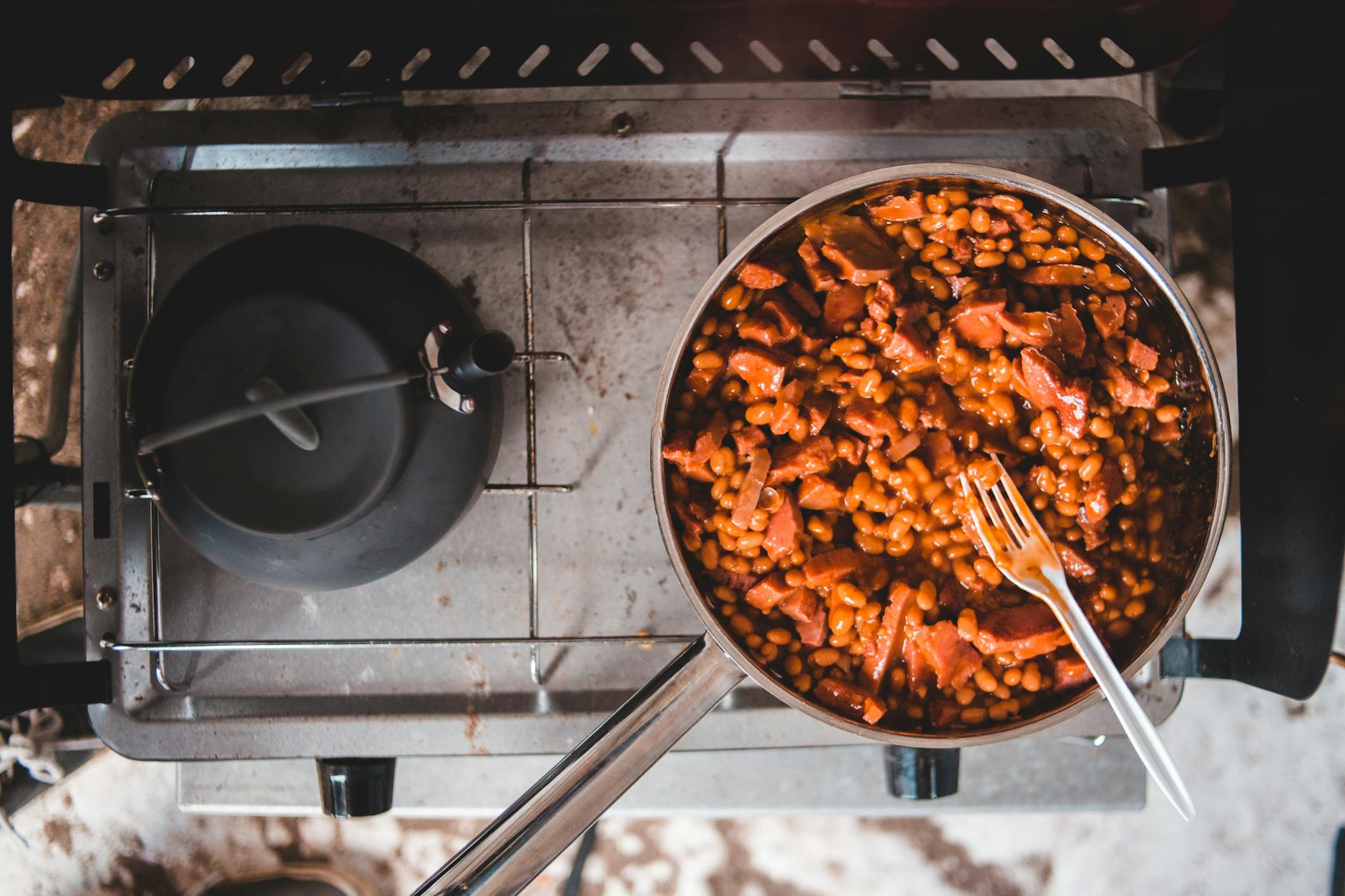 delicious beans with bits of sausages in a pan