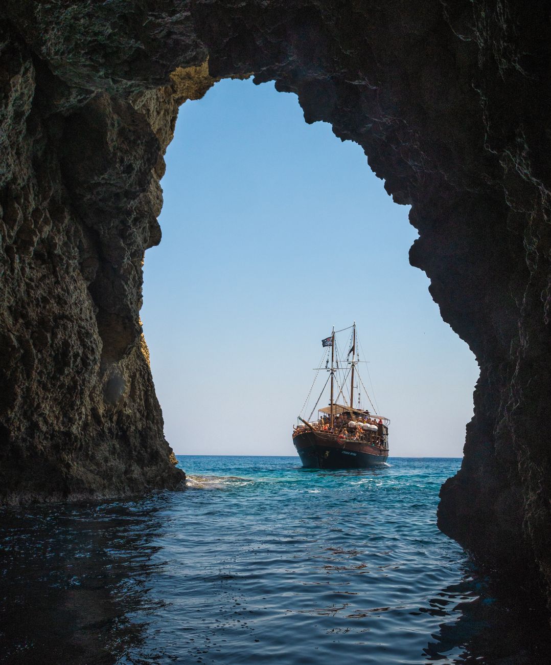 brown boat on body of water towards tunnel