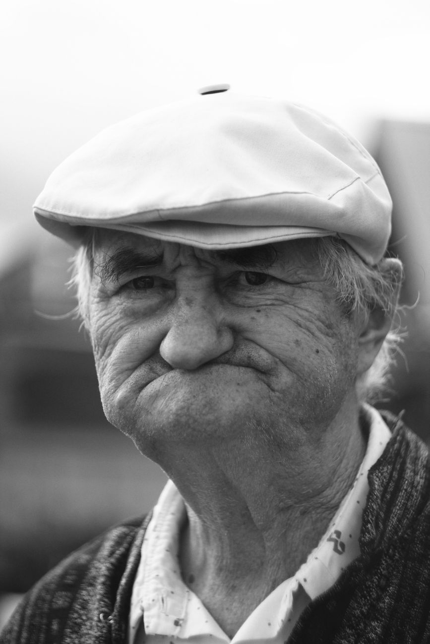 grayscale photo of an elderly man with a hat