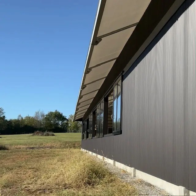 Side view of a covered riding arena featuring large sliding windows for airflow and daylight.