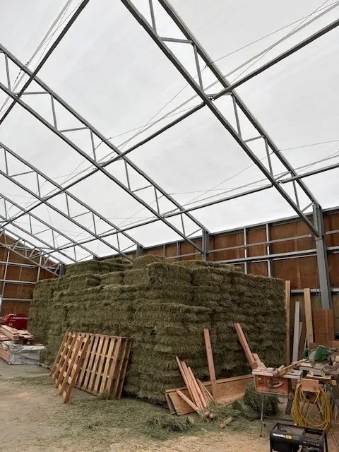Hay storage area inside a spacious horse barn with engineered steel framing.