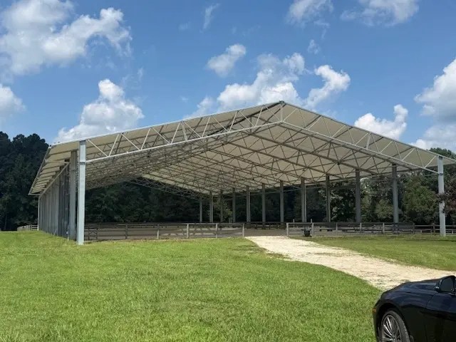 Open-sided covered riding arena designed for year-round horse riding and training.