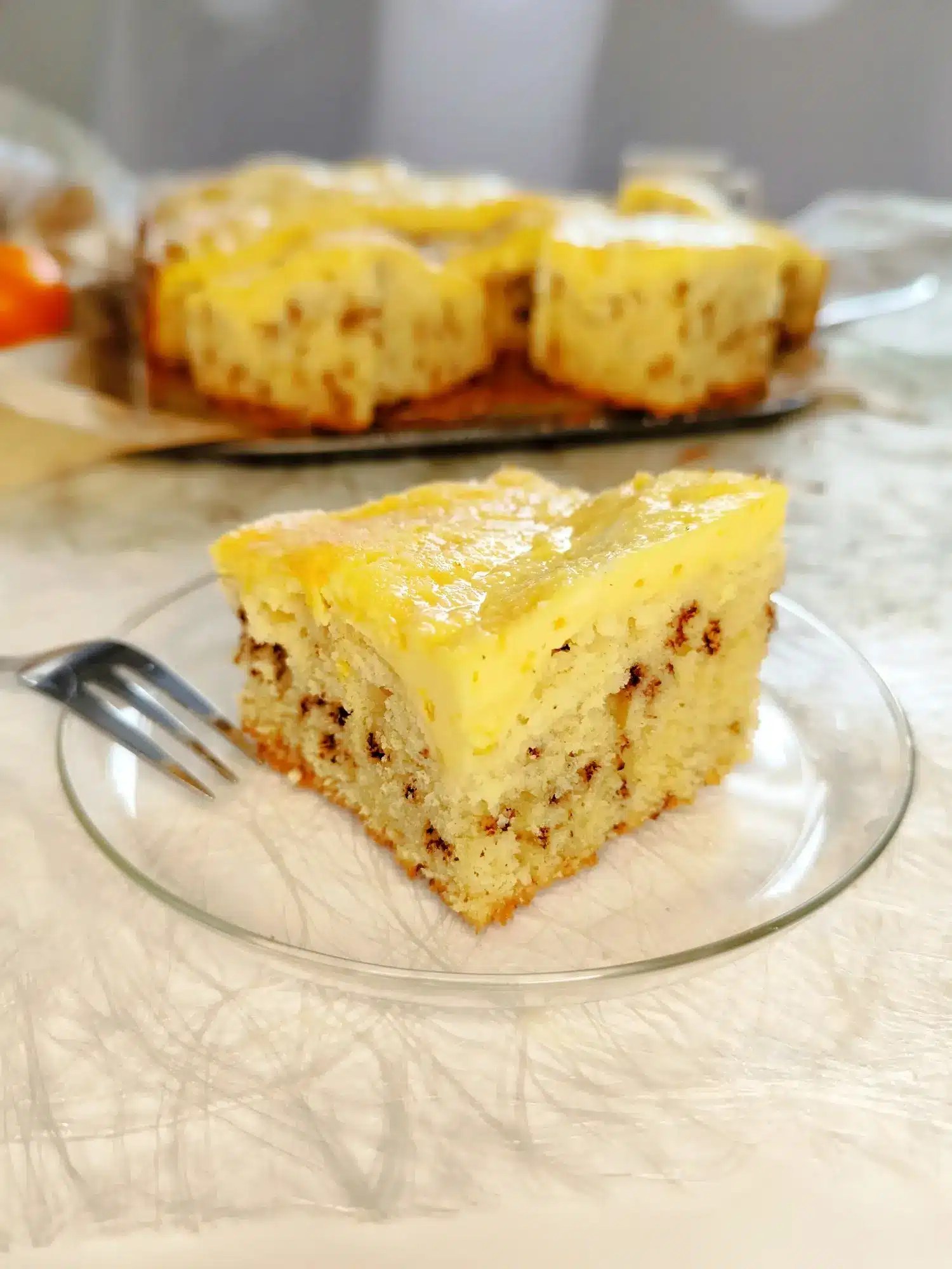 Saftiger Ameisenkuchen aus Rührteig, bedeckt mit einer cremigen Quark-Mandarinenschicht, auf einem Teller angerichtet