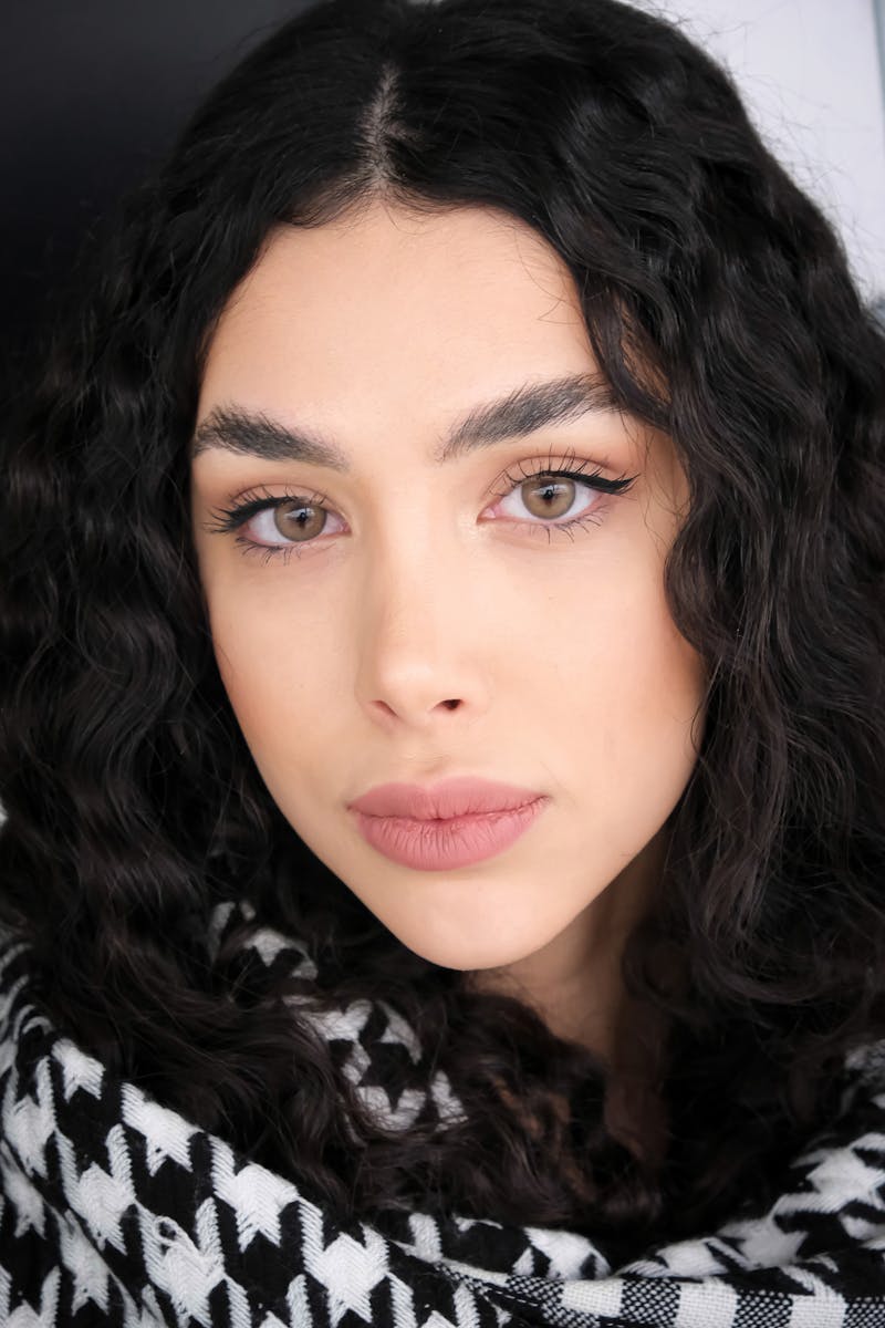 Close-up portrait of a woman with curly hair and striking makeup