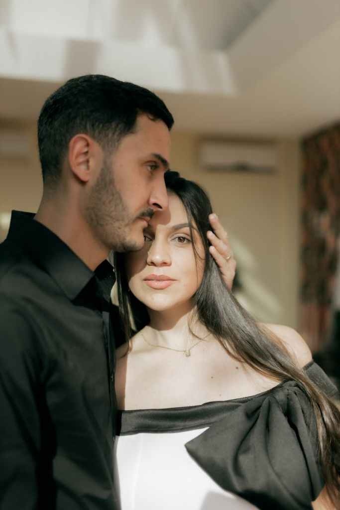 A loving couple shares a tender moment indoors, bathed in soft daylight.