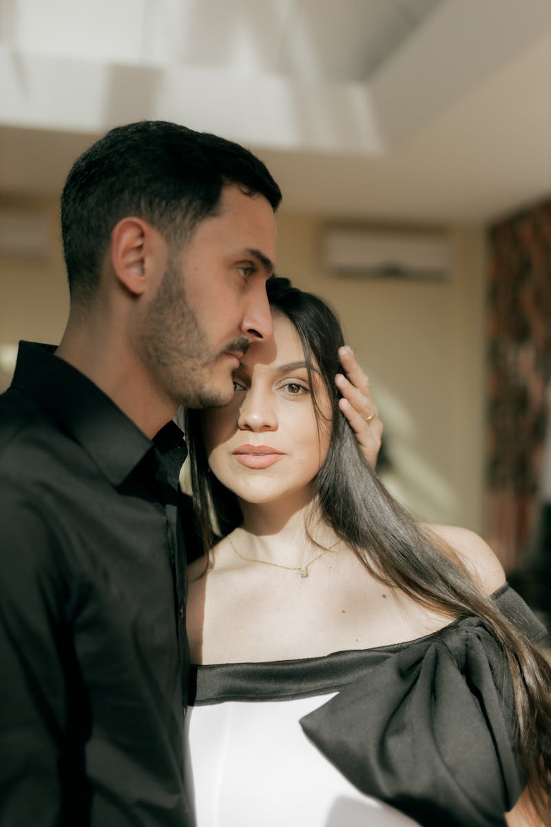 A loving couple shares a tender moment indoors, bathed in soft daylight.