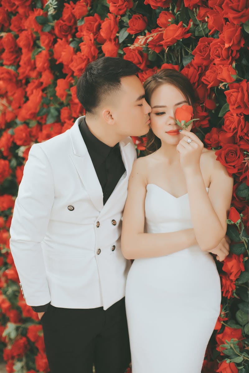 A romantic moment of a couple by a wall of red roses.
