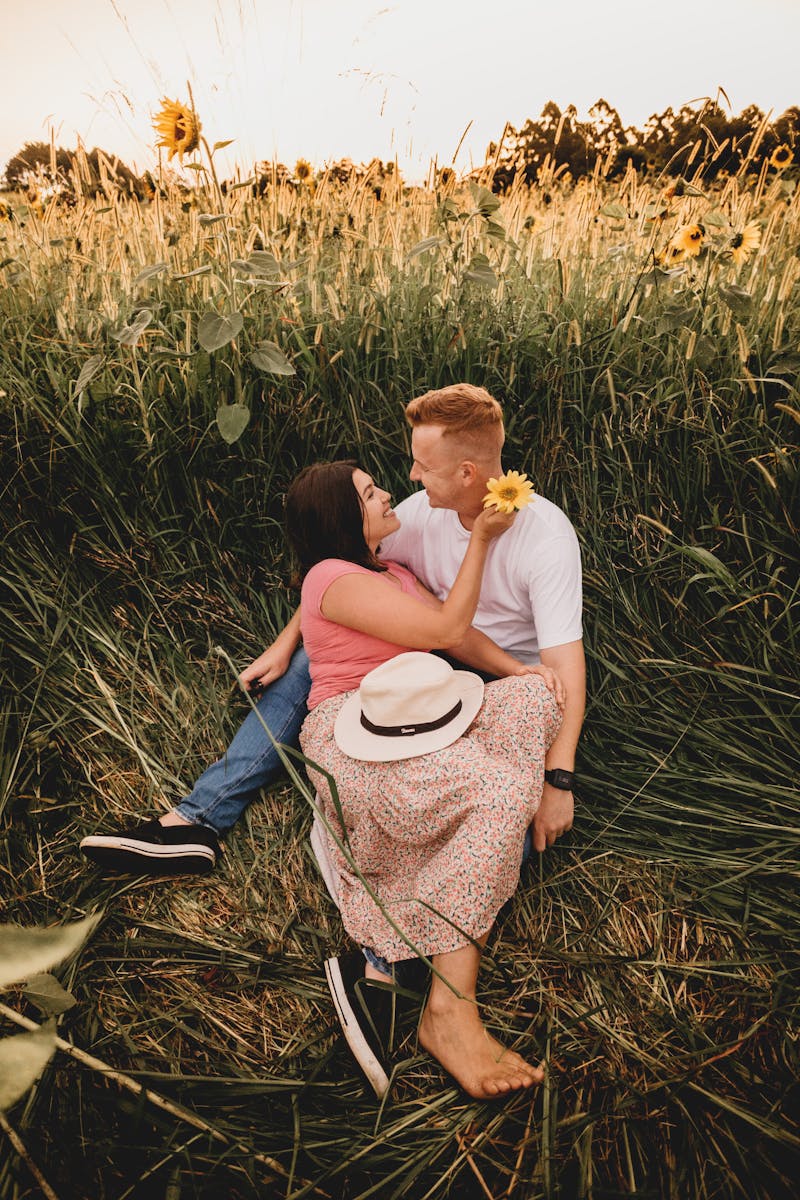 A couple shares a tender moment in a sunlit sunflower field, radiating love and happiness.