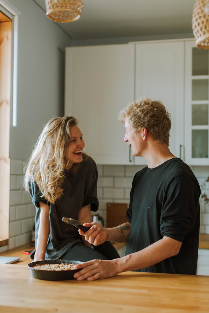 A cheerful couple shares a light moment while preparing food in their cozy kitchen.