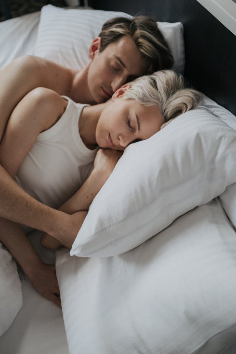 A loving couple embraces while sleeping peacefully in a cozy bed setting.