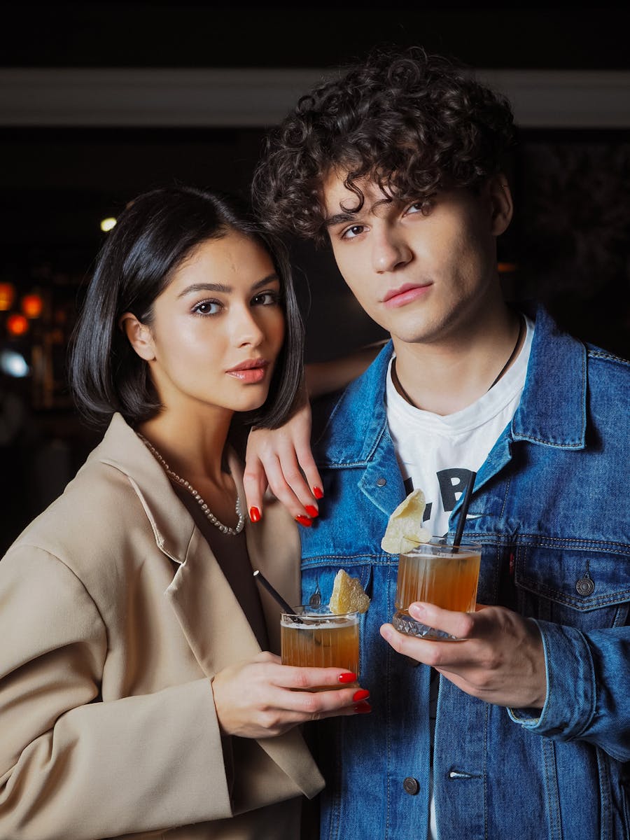 Chic couple holding cocktails in a cozy bar setting, exuding lifestyle vibes.