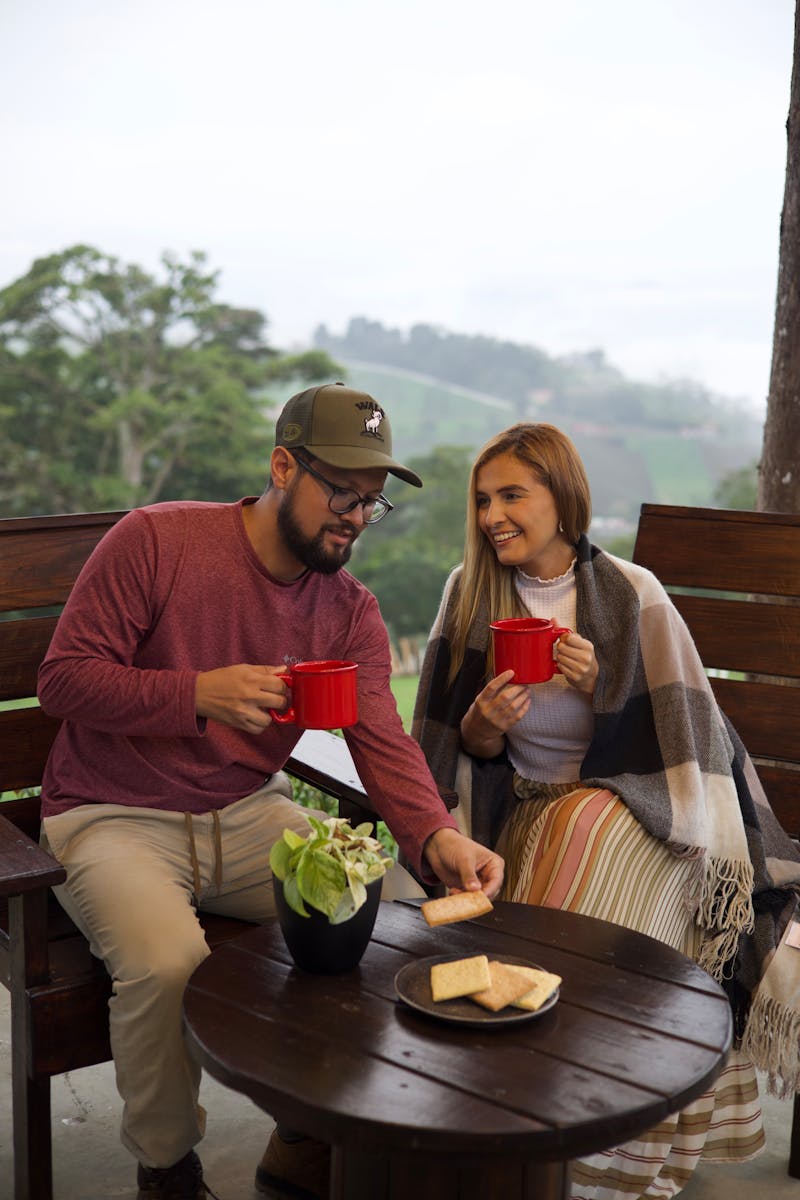 A happy couple sitting outdoors, enjoying tea and snacks on a cozy patio.