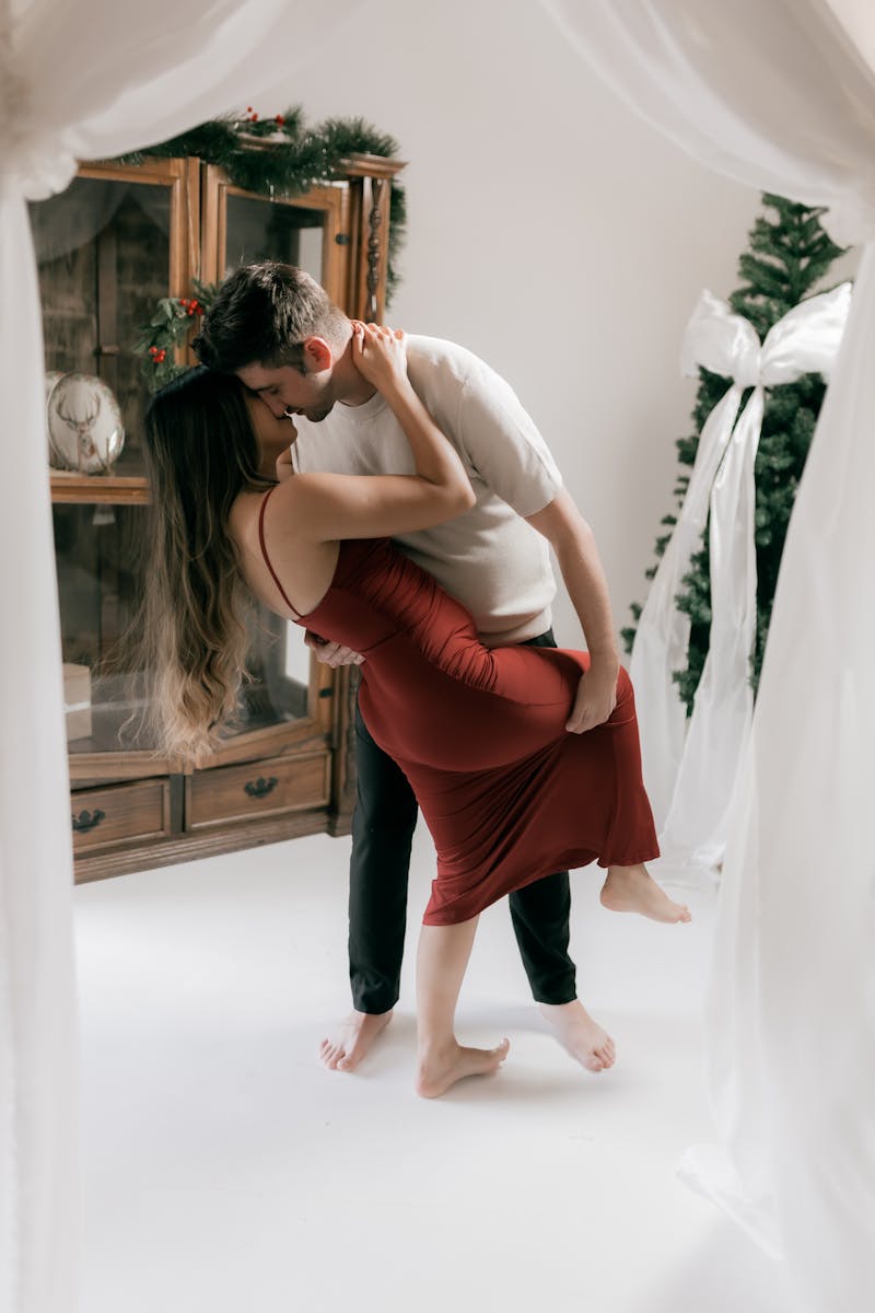 A romantic couple dancing indoors during a festive holiday celebration.