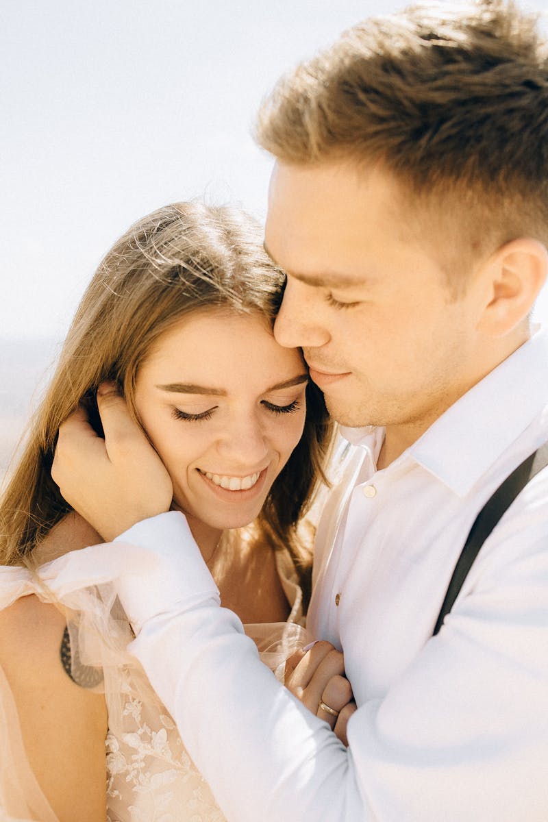 Smiling couple in a loving embrace on a sunny day, showcasing romance and happiness.