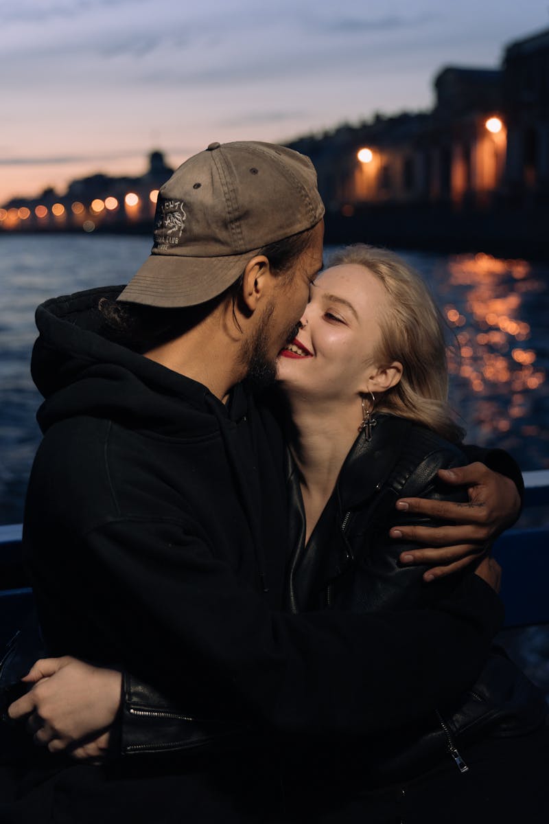 A couple shares a romantic embrace on a boat during sunset, reflecting love and intimacy.
