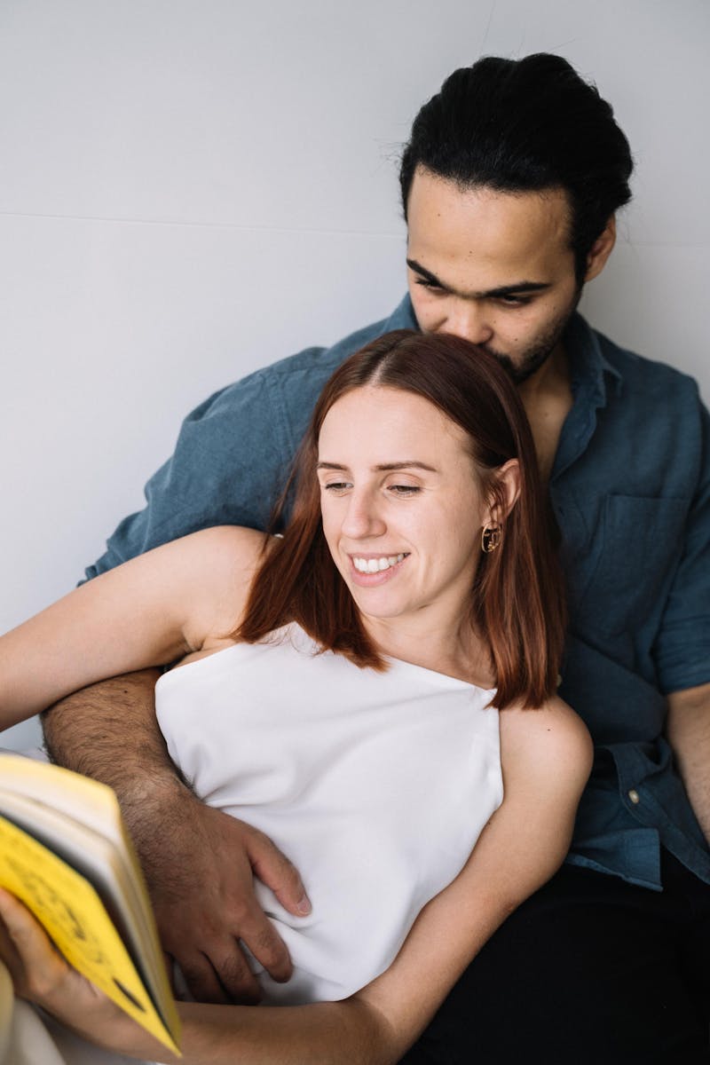 A joyful couple sitting close, enjoying a book together indoors.