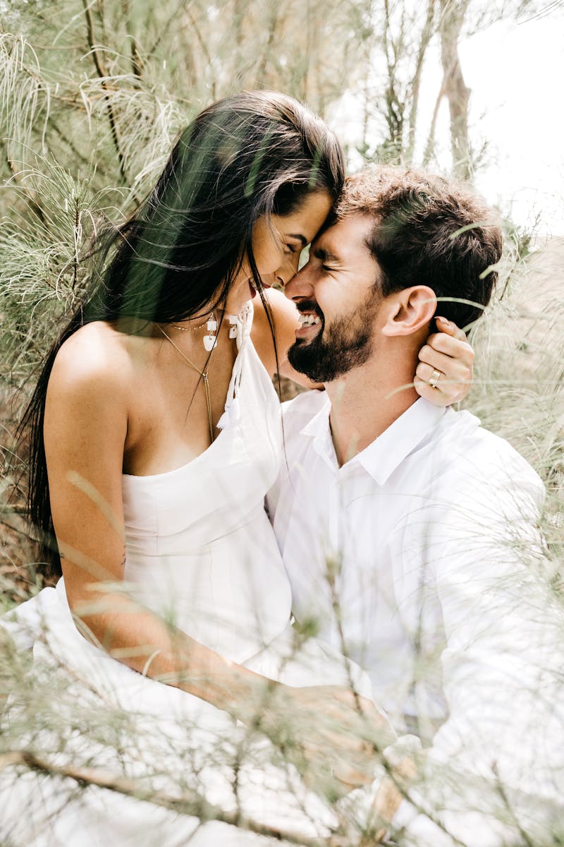 A joyful, romantic couple embracing in a sunlit outdoor setting, expressing love and connection.