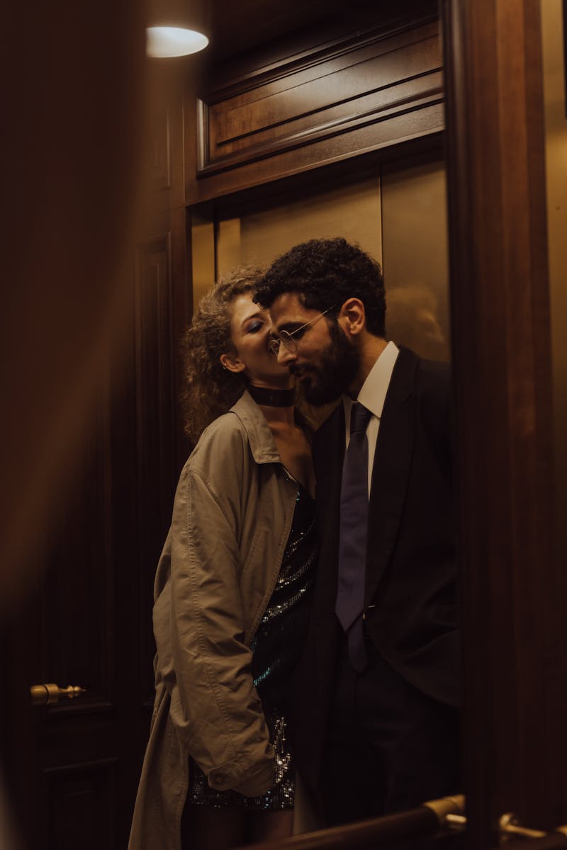 A couple sharing a tender moment in an elegant elevator setting.
