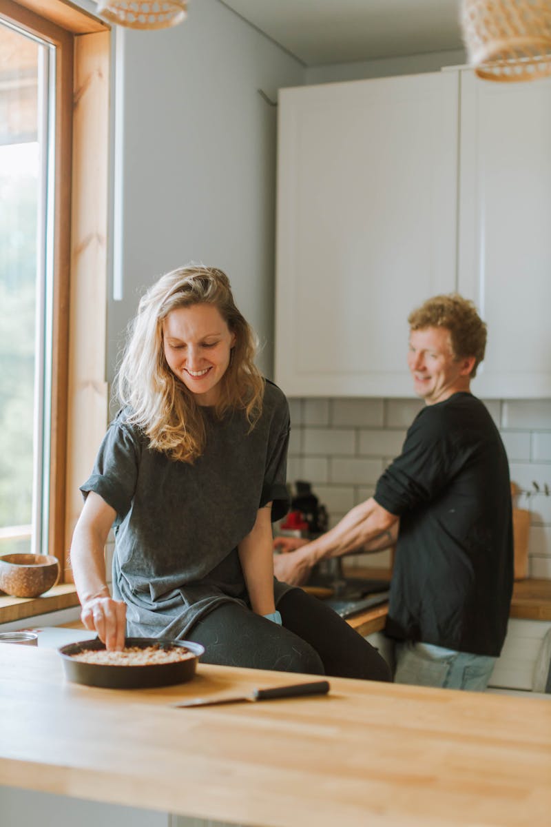 A joyful couple cooking together in their modern kitchen, smiling and engaged.