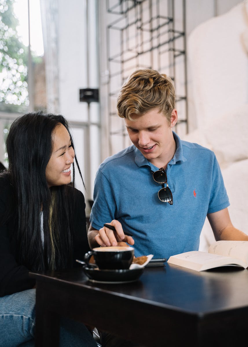 A joyful couple enjoying reading and coffee in a cozy cafe setting.