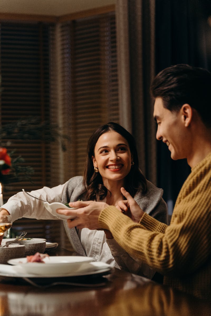 A joyful couple smiling and dining together, celebrating a special moment indoors.