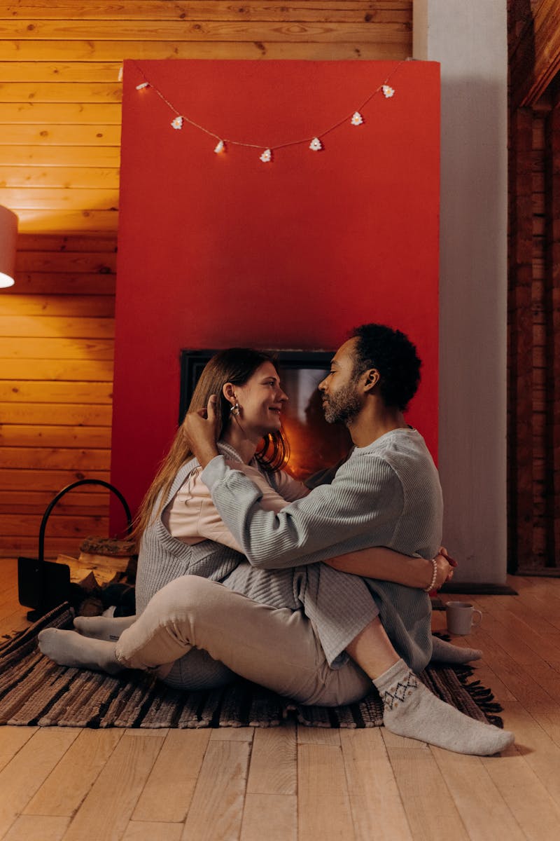 A loving couple sharing an intimate moment by a glowing fireplace in a cozy home setting.
