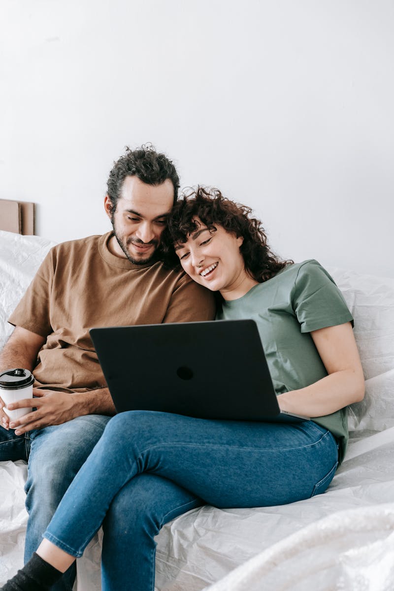 Smiling couple enjoying leisure time on the sofa using a laptop at home.