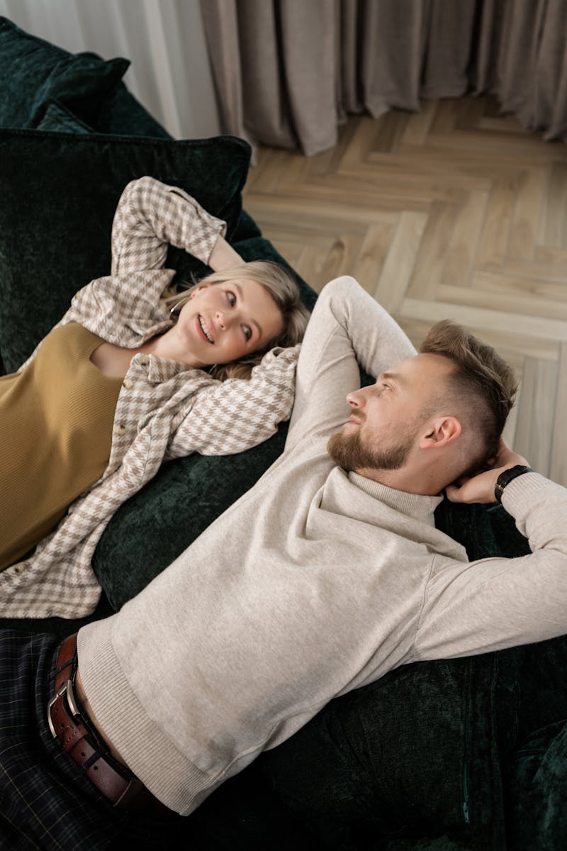 Couple relaxing indoors on a stylish sofa, enjoying a carefree moment together.