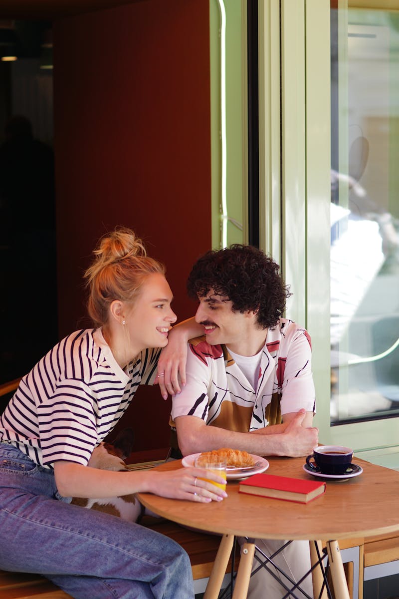 A couple sharing a warm moment at a café table with coffee and pastries.
