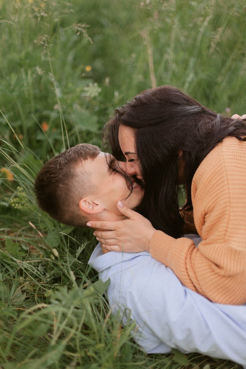 A couple sharing a romantic moment lying in green grass, symbolizing love and affection.