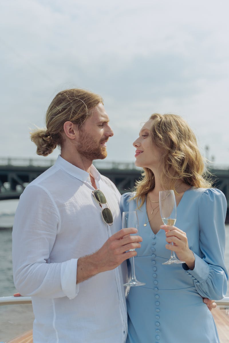 A couple enjoys a romantic moment with champagne on a sunny day outdoors.