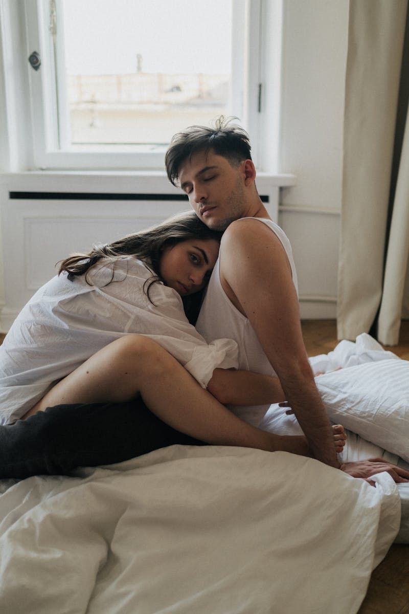 A couple embracing affectionately on a bed in a cozy room.